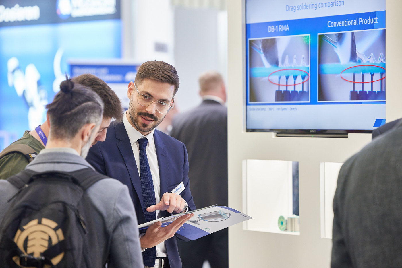 Ein Almit-Mitarbeiter erläutert einem Messebesucher am Stand den Vergleich zweier Lötverfahren