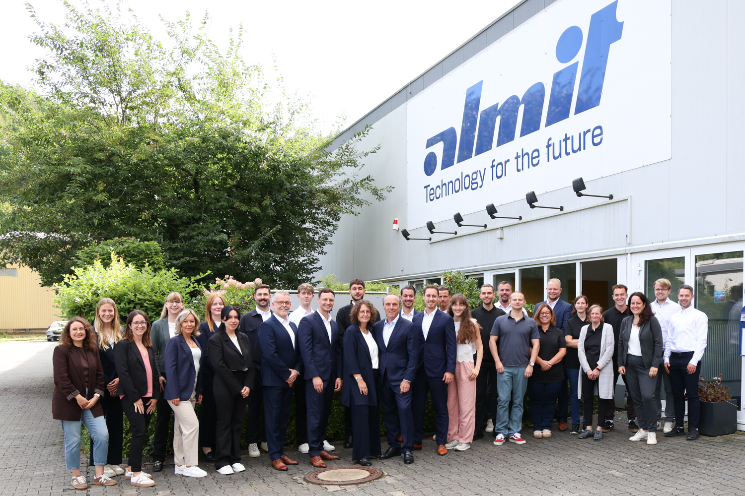Die Belegschaft der Almit GmbH vor dem Firmengebäude in Michelstadt, über dem Eingang der Schriftzug „almit – Technology for the future“