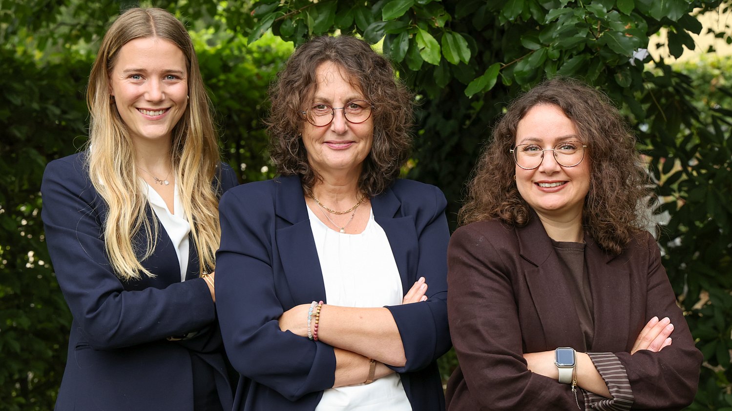 Das Team Human Resources von Almit, drei Personen vor einer Hecke