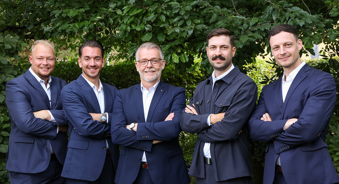 Das Team Sales von Almit, fünf Personen vor einer Hecke