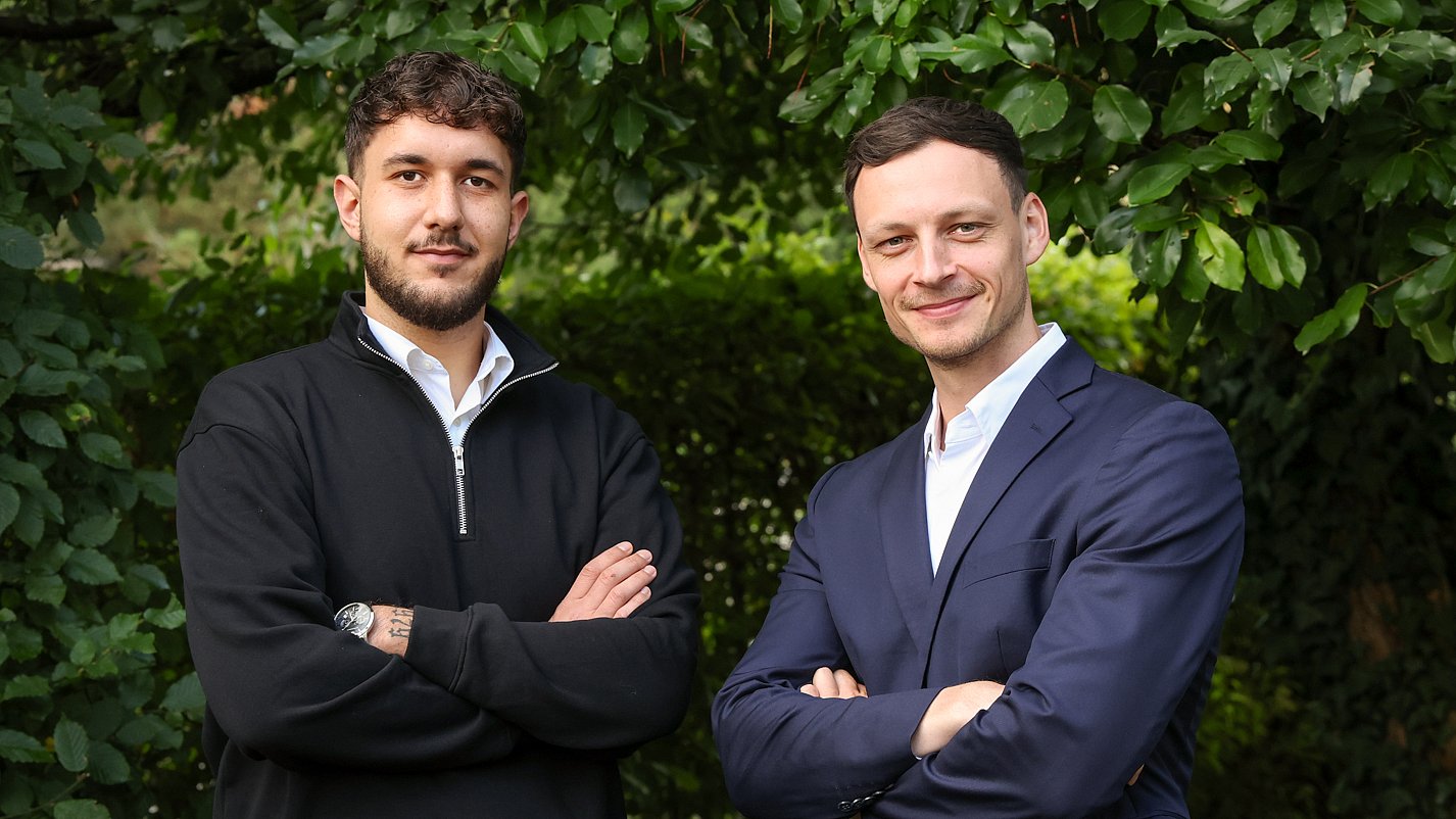 Das Team Einkauf von Almit, zwei Personen vor einer Hecke